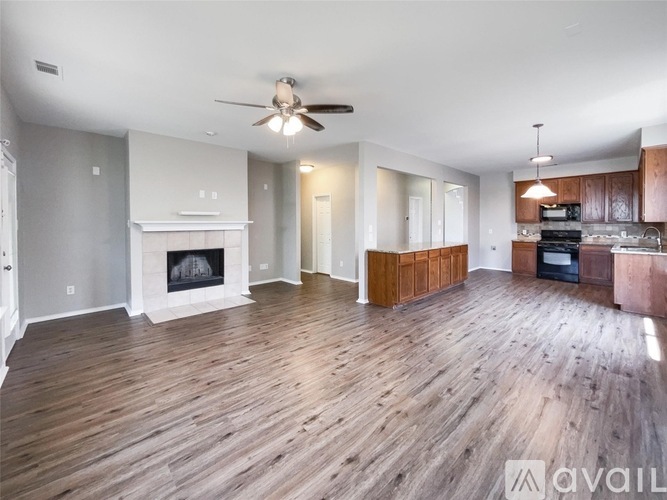 A spacious living room with wood flooring and a fireplace.