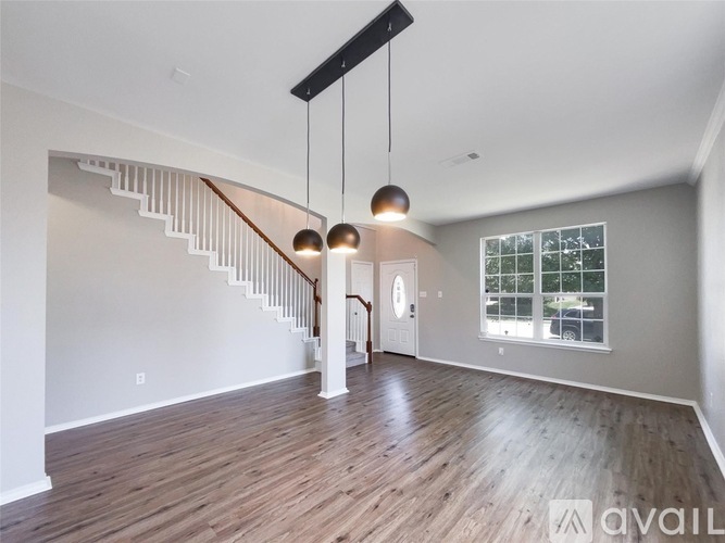 A spacious room with wooden floors and a staircase with a wooden handrail.