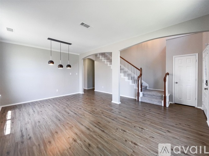A spacious room with wooden flooring and a staircase leading to another room.