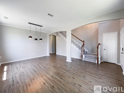 A spacious room with wooden flooring and a staircase leading to another room.