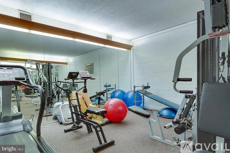 A gym with a variety of equipment including a treadmill, weights, and a bench.