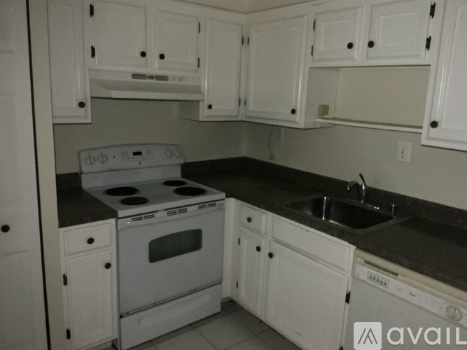 A kitchen with white cabinets and a black countertop.