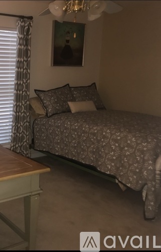 A bedroom with a bed, a table, and a painting on the wall.