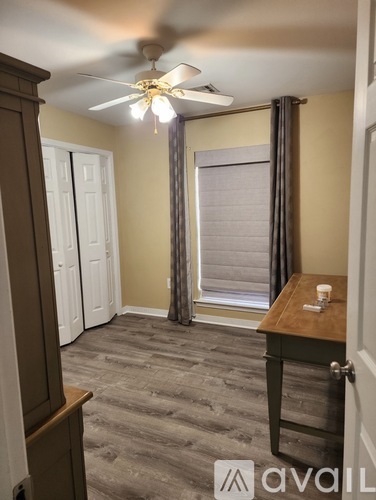 A room with a ceiling fan and a table with a cup on it.