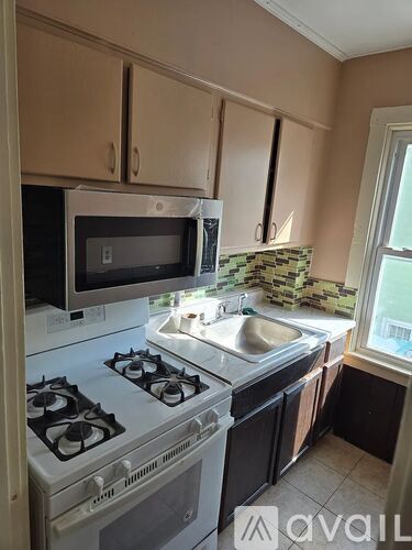 A kitchen with a stove, microwave, and sink.