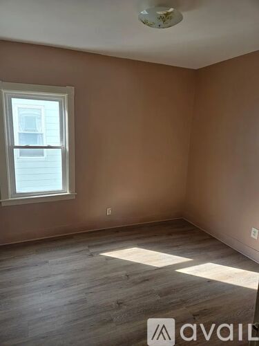 A room with wooden floors and a window letting in sunlight.