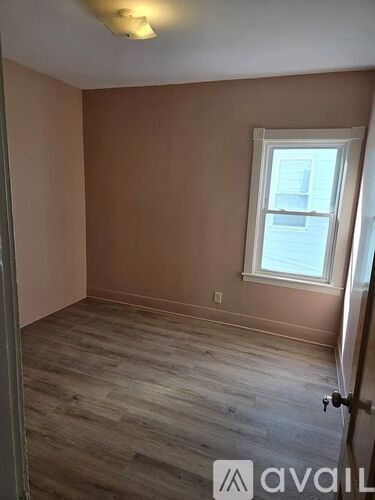 A room with a window and wooden flooring.
