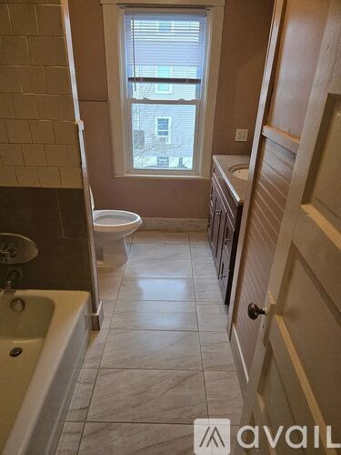 A bathroom with a tub, toilet and window.