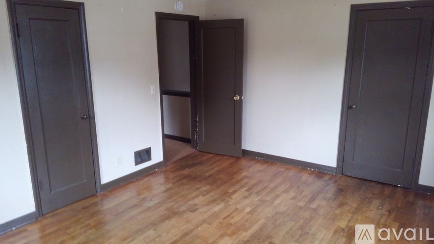 A room with wooden floors and three doors.