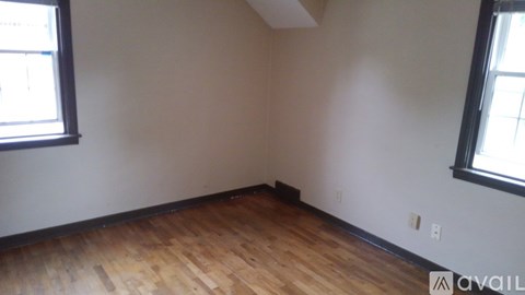 A room with wooden floors and two windows.