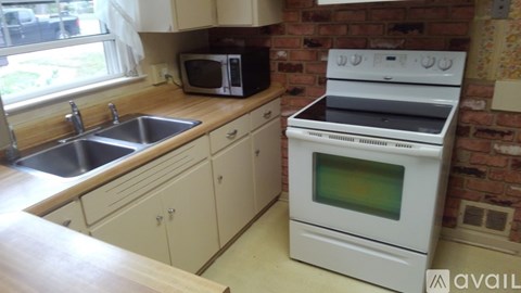 A white oven sits in a kitchen with a brick wall.