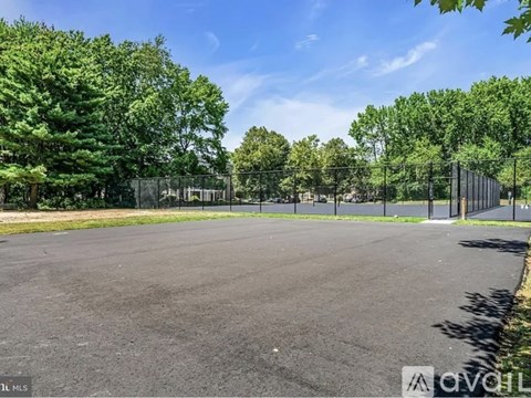 A large, empty parking lot surrounded by a fence and trees.