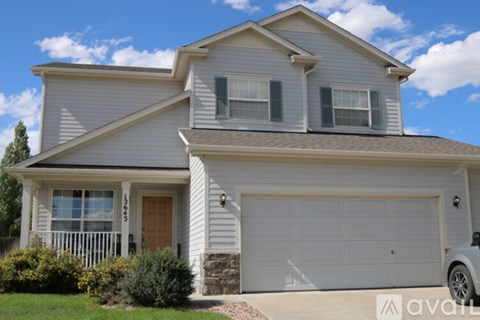 A two-story house with a garage and a car parked in front.