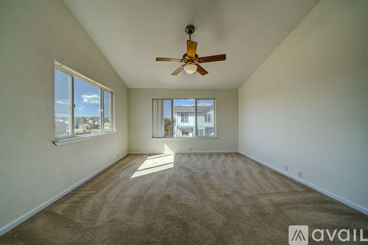 A room with a ceiling fan and carpeted floor.