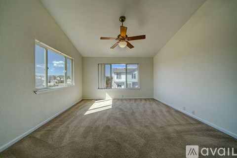 A room with a ceiling fan and carpeted floor.