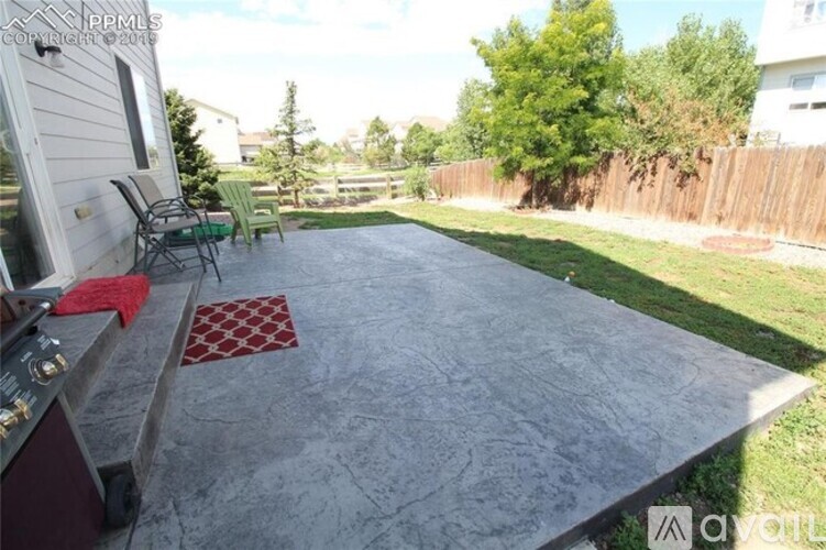 A backyard with a concrete patio and a grill.