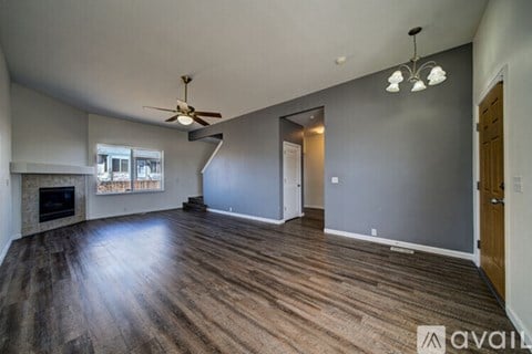 A spacious living room with wood flooring and a ceiling fan.
