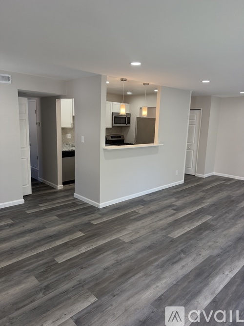 A spacious room with a kitchen area in the background.