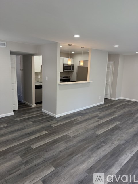 A spacious room with a kitchen area in the background.