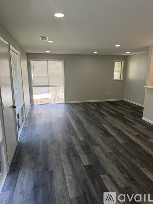 A room with wooden flooring and a window with blinds.