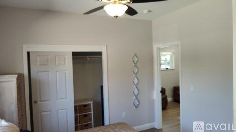 A bedroom with a white door and a ceiling fan.
