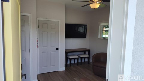 A living room with a brown couch and a flat screen TV mounted on the wall.