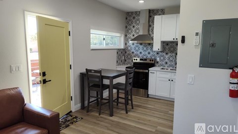 A kitchen with a yellow door and a dining table with chairs.