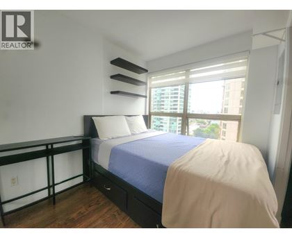 A bedroom with a bed, nightstand, and window.