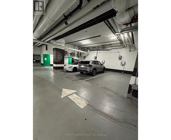 A car is parked in a parking garage with a green sign on the wall.