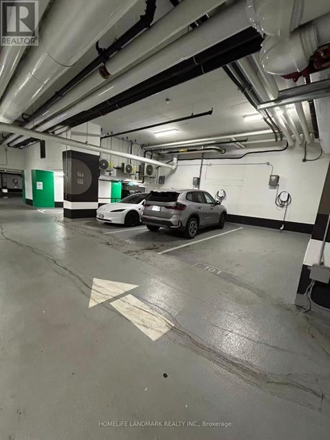 A car is parked in a parking garage with a green sign on the wall.