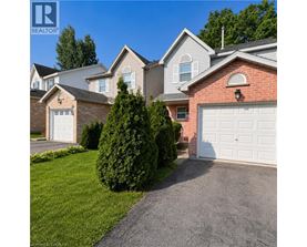 A house with a white garage door is surrounded by greenery.