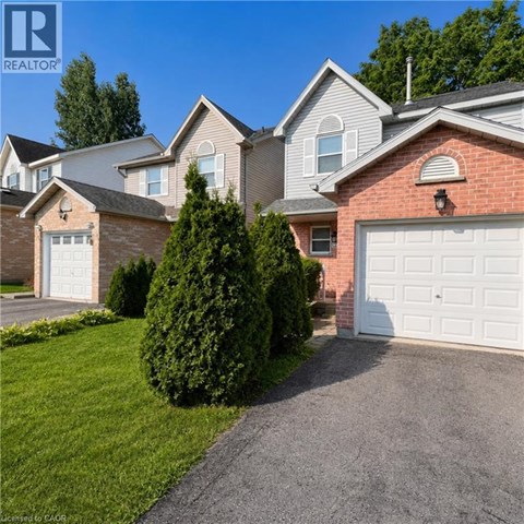 A house with a white garage door is surrounded by greenery.