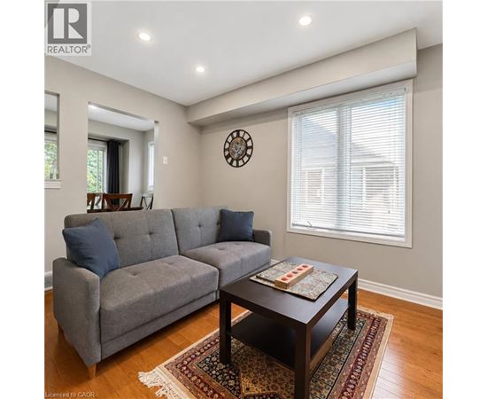 A grey couch sits in a living room with a clock on the wall.