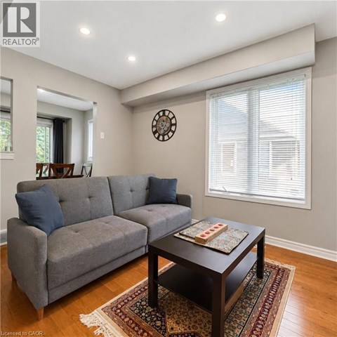 A grey couch sits in a living room with a clock on the wall.
