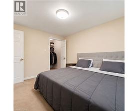 A bedroom with a large bed and a closet with clothes hanging inside.