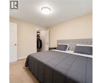A bedroom with a large bed and a closet with clothes hanging inside.