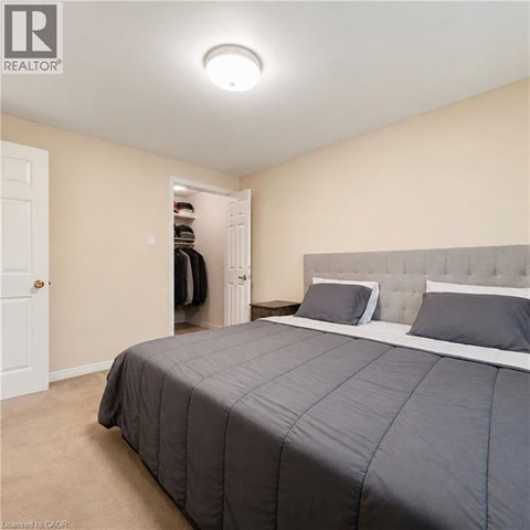 A bedroom with a large bed and a closet with clothes hanging inside.