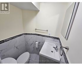 A bathroom with a marble tile wall and a white sink.