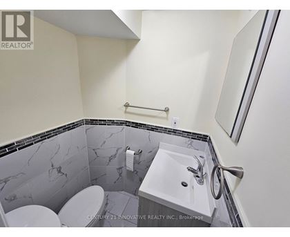 A bathroom with a marble tile wall and a white sink.