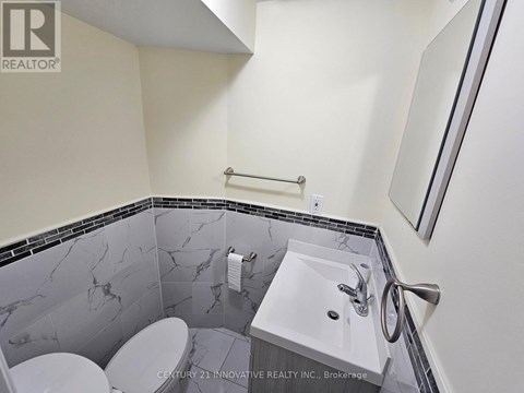 A bathroom with a marble tile wall and a white sink.