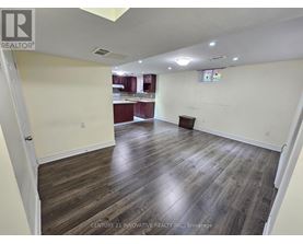 A spacious room with wooden flooring and white walls.