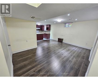 A spacious room with wooden flooring and white walls.
