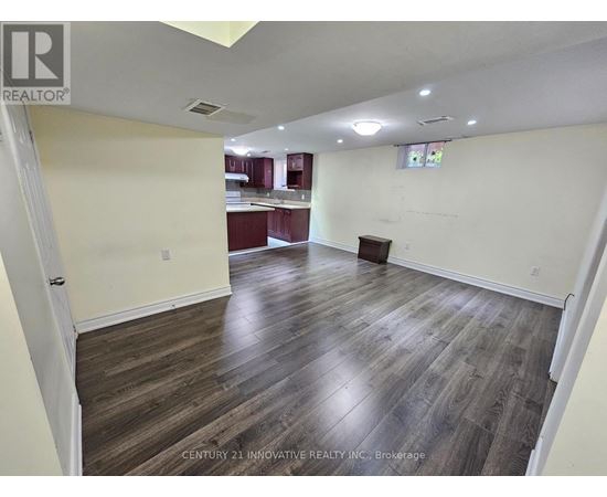 A spacious room with wooden flooring and white walls.