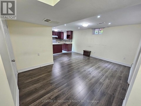 A spacious room with wooden flooring and white walls.