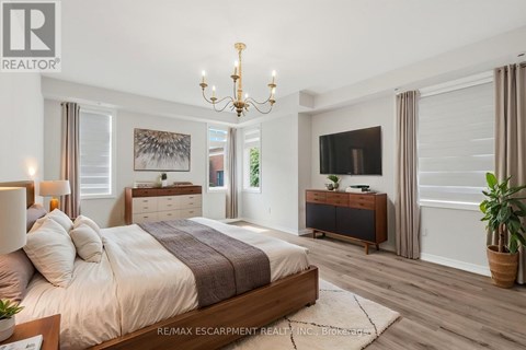 A bedroom with a large bed, a chandelier, and a flat-screen TV.