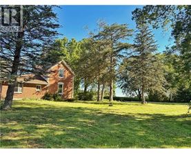A house is surrounded by trees in a grassy field.