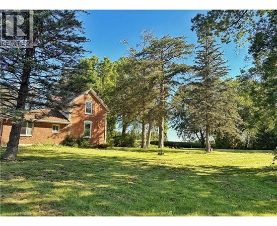A house is surrounded by trees in a grassy field.