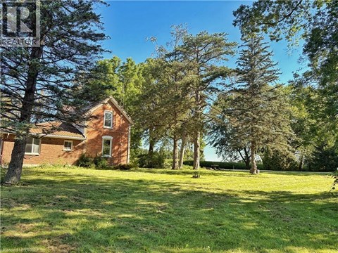 A house is surrounded by trees in a grassy field.