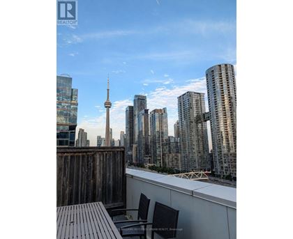A cityscape with a wooden deck and chairs in the foreground.