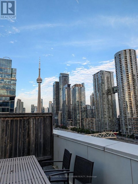 A cityscape with a wooden deck and chairs in the foreground.